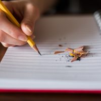 yellow pencil on lined paper with red binding.